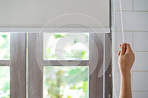 Woman pull rope, opened modern white  blinds