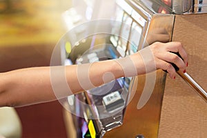 Woman pulling the handle on a slot machine in a casino.