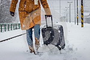 Woman pulling heavy luggage at a snow railroad station