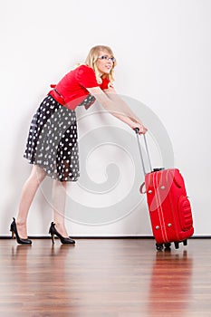 Woman pulling heavy red travel bag