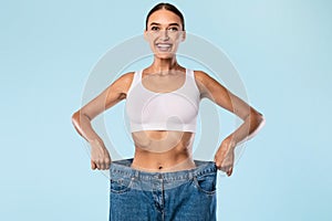 Woman Pulling Her Old Large Loose Jeans And Posing