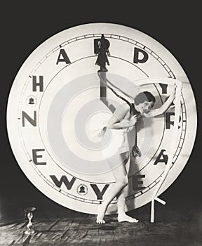 Woman pulling the hour hand of giant clock on New Year's Eve