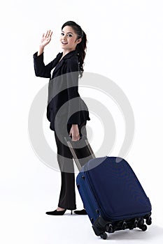 A woman pulling a luggage and waving hand