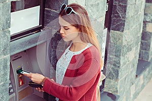 Woman pulling out money from debit card at an ATM. Girl uses credit card to withdraw at Bank cash terminal