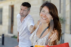 woman pulling reluctant man into shops with