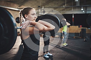 Woman pulling up large barbell in fitness class