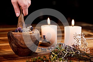 Woman is pulverising healing herbs and flowers into a mortar, ritual cleansing