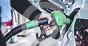 Woman pumping gasoline fuel in car at gas station.