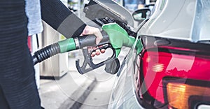 Woman pumping gasoline fuel in car at gas station.