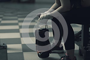 Woman with punching gloves resting on a bench