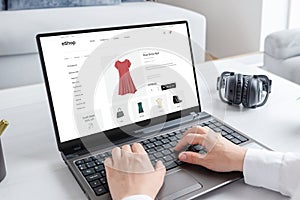 Woman purchasing a stunning red dress online with laptop computer photo