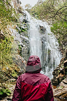 Woman in a purple oilskin standing in front of a giant waterfall