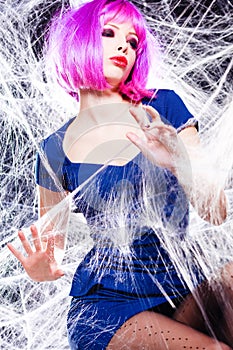 Woman with purple wig and intense make-up trapped in a spider web