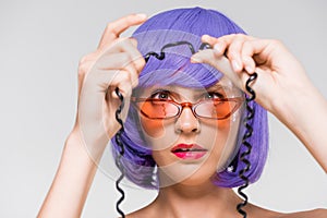 Woman in purple wig looking at cord of vintage telephone