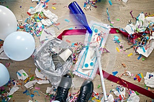 Woman with pushbroom cleaning mess of floor in room after party confetti