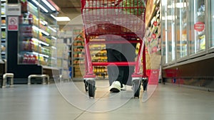 Woman pushing a cart in a supermarket store in slow motion, close-up shot from a low angle. Grocery shopping concept