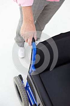 Woman pushing empty wheelchair