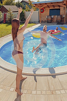 Woman pushing a man into the swimming pool