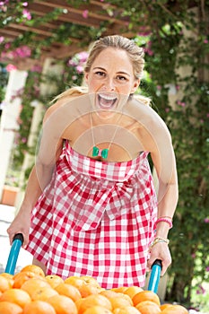 Woman Pushing Wheelbarrow Filled With Oranges