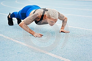 Woman, pushups and track for sports, exercise and warm up in stadium or field for fitness. Female athlete, training and