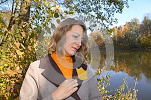 The woman put an autumn leaf of tulip lyriodendron to her coat. Autumn Park