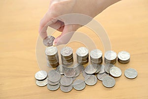 A woman put coins to stack of coins