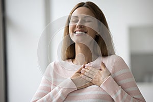 Woman put folded palms on chest, feeling thankful express gratitude