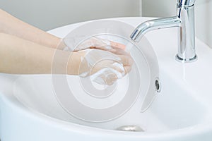 Woman put her hands under lavatory tap water for wash or clean with soap foam that cover around her hand. Concept good health and