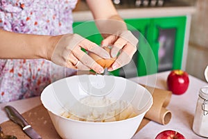 Woman put ingredients for apple pie into big white bowl. Preparing dough in the kitchen