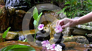 Woman put a pink flower on top of pyramid stone stack.