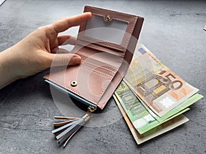 woman puts 50 100 euros in wallet or caunt money. Saving concept