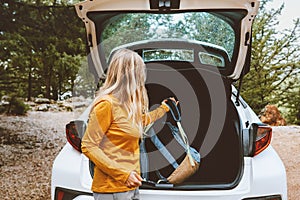 Woman puts backpack in a car trunk road trop vacations travel active lifestyle outdoor photo