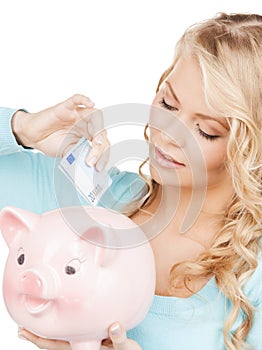 Woman puts cash money into big piggy bank