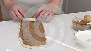 The woman puts the cinnamon filling on the rolled dough.  Collapses it.  For baking sinabons.  Close-up shot