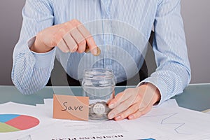 Woman puts coin into jar labelled Save.