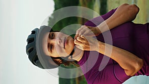 Woman puts on cycling helmet. Cyclist putting on helmet. Vertical concept