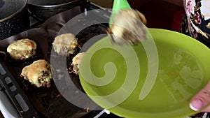 A woman puts the finished dish on a plate. Minced meat steaks with potatoes, eggs and cheese.