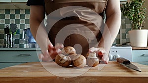 Woman puts fresh champignons on wooden cutting board. Eco-friendly lifestyle, organic healthy food preparation. Cozy