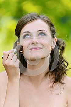 Woman puts on her face powder brush