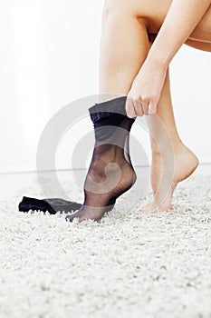 a woman puts on her legs tights slender legs black tights