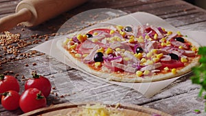 Woman puts ingredients on the dough while making pizza in the kitchen