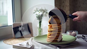 Woman puts pancake from pancake pan on top of pancake stack. Pancakes breakfast