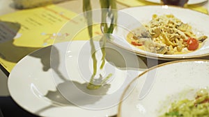 A woman puts pasta with a fork and spoon into a plate.