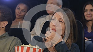 Woman puts popcorn into her mouth at the movie theater