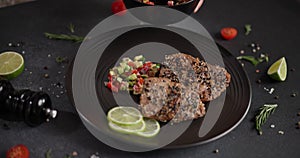 Woman puts salsa garnish onto plate with grilled fried tuna steak covered with sesame seeds