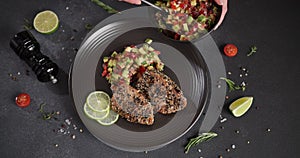 Woman puts salsa garnish onto plate with grilled fried tuna steak covered with sesame seeds