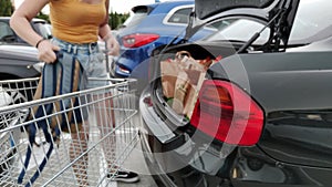 woman puts shopping in the trunk of a car. purchases in cardboard packages