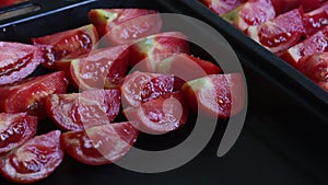 The woman puts the sliced tomatoes on a baking sheet. Cooking sun-dried tomatoes in olive oil. Close-up shot