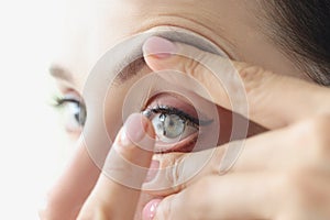 Woman puts on soft contact lenses closeup