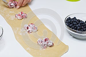 A woman puts starchy cherries on the rolled dough. Cooking dumplings photo